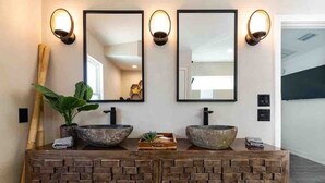 A bathroom with two large stone sinks, a wooden vanity, and three wall-mounted mirrors with light fixtures. - Pool, Hot Tub, 50 steps to sand, Pool table (St. Augustine)