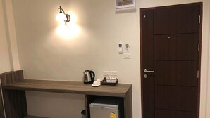 A kitchenette with a countertop, a kettle, a coffee maker, a mini-fridge, and a door with a handle. - The Hub Suratthani Hotel (Surat Thani)