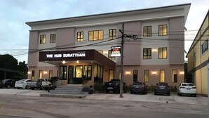 A two-story building with a sign reading "The Hub Surat Thani". There are several parked cars in front. - The Hub Suratthani Hotel (Surat Thani)