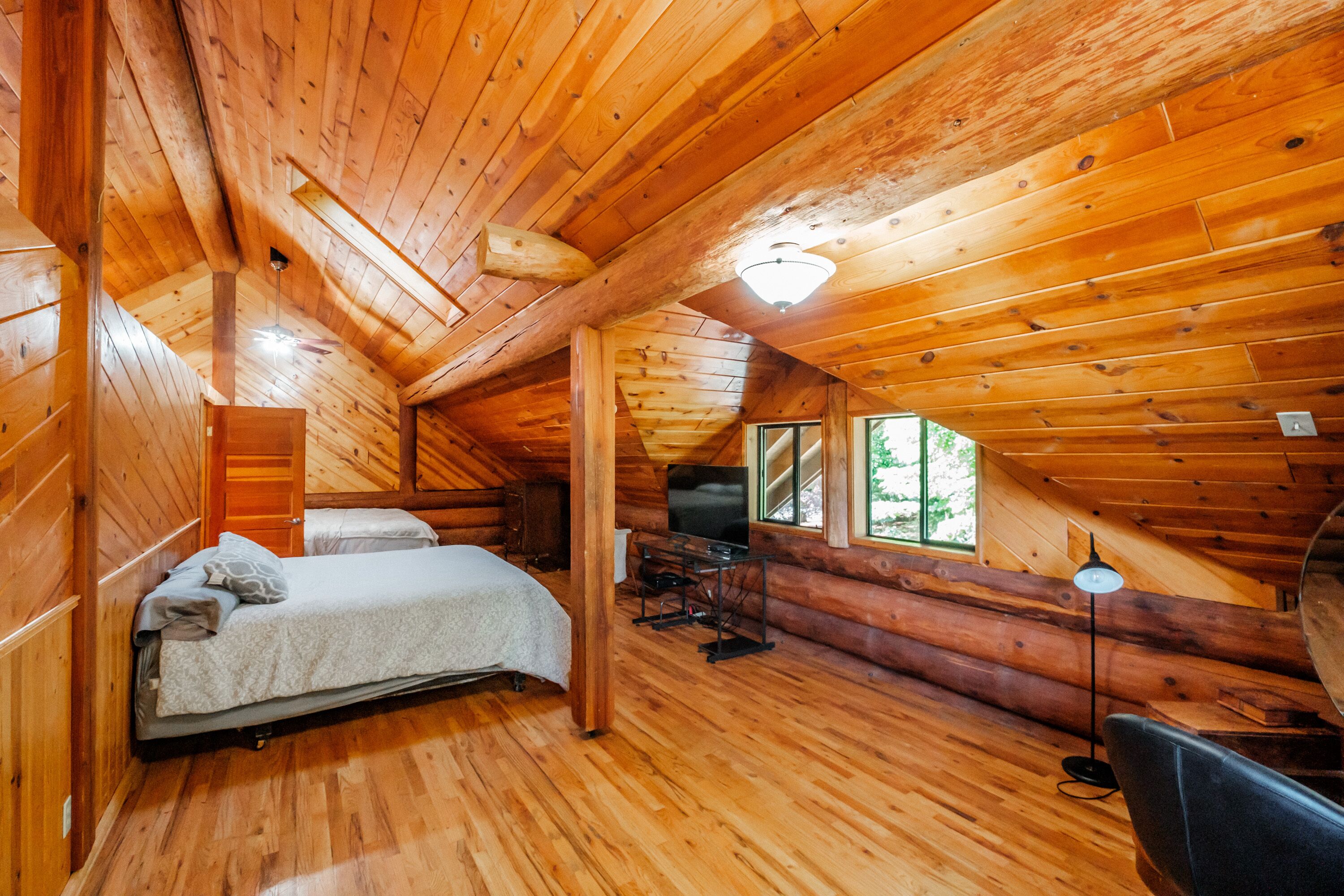 Accogliente camera da letto in una baita di legno, con un letto, una scrivania e una televisione.
