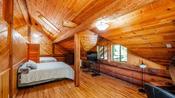 Accogliente camera da letto in una baita di legno, con un letto, una scrivania e una televisione.