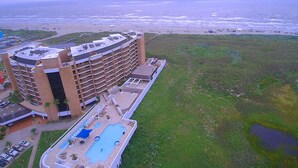 A hotel with multiple floors, a rooftop pool, and a view of the beach and ocean.