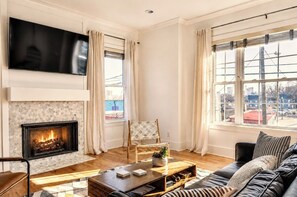Una sala de estar con chimenea, televisor, sofá y vistas a la ciudad.