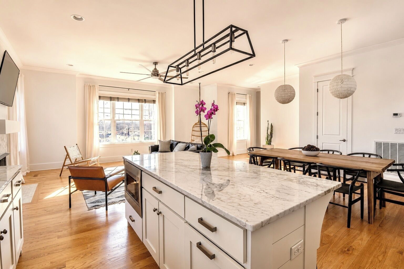 Una cocina moderna con una isla central, una mesa de comedor de madera e iluminación colgante.
