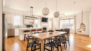 Una cocina moderna con comedor, piso de madera y una silla colgante.