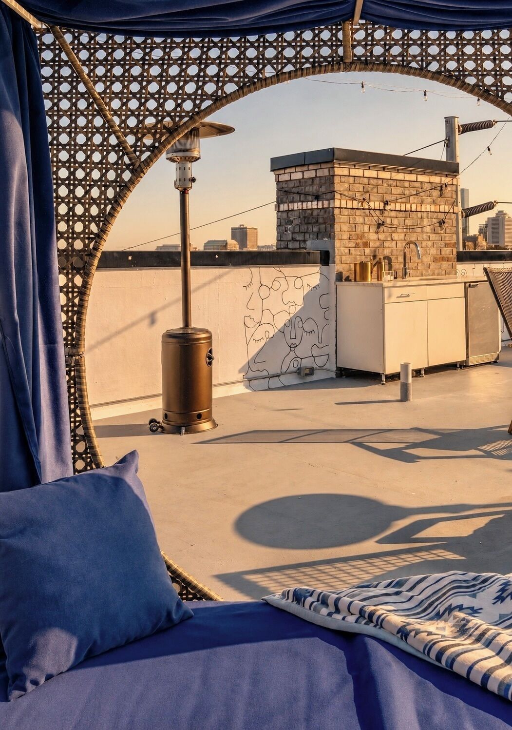 A rooftop terrace with a bed, a water dispenser, and a view of the cityscape.