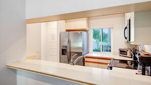 Een moderne keuken met een roestvrijstalen koelkast, een inbouwoven en een raam met uitzicht op groen.