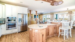 A spacious kitchen with modern appliances, a central island, and a view of the outdoors. - Paradise Point: Luxury Beachfront Home with Views (Pawleys Island)