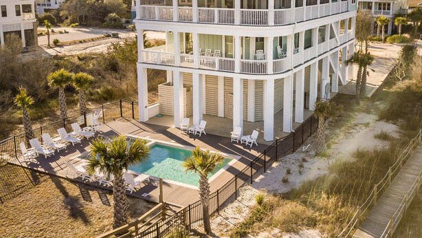 A two-story beachfront house with a pool, multiple balconies, and a deck area with lounge chairs. - Paradise Point: Luxury Beachfront Home with Views (Pawleys Island)