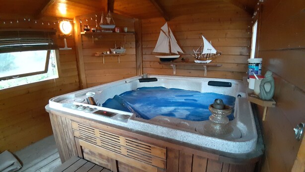 Een houten chalet met een jacuzzi, een houten terras en een raam.
