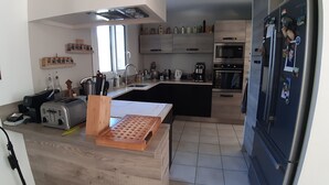 Een moderne keuken met een centraal eiland, inbouwapparatuur en een grote koelkast.