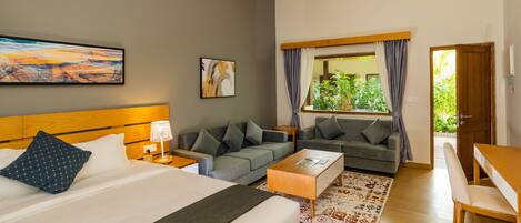 A hotel room with a bed, two sofas, a coffee table, and a window with curtains.