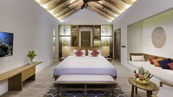 A modern bedroom with a large bed, a bench, a small table with fruit, and a ceiling fan.