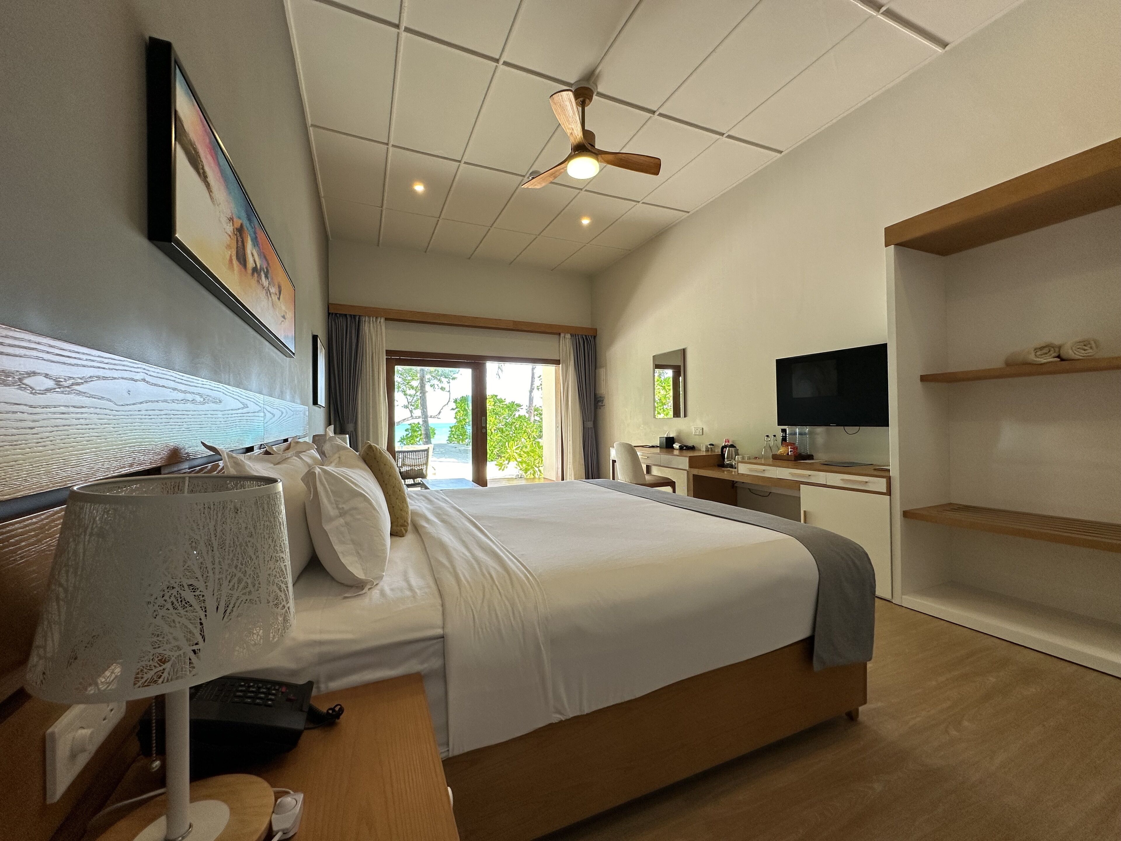 Habitación de hotel con cama, escritorio, televisor y vistas al exterior.