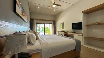 Habitación de hotel con cama, escritorio, televisor y vistas al exterior.