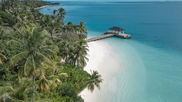 A beach with a wooden pier leading to a gazebo.