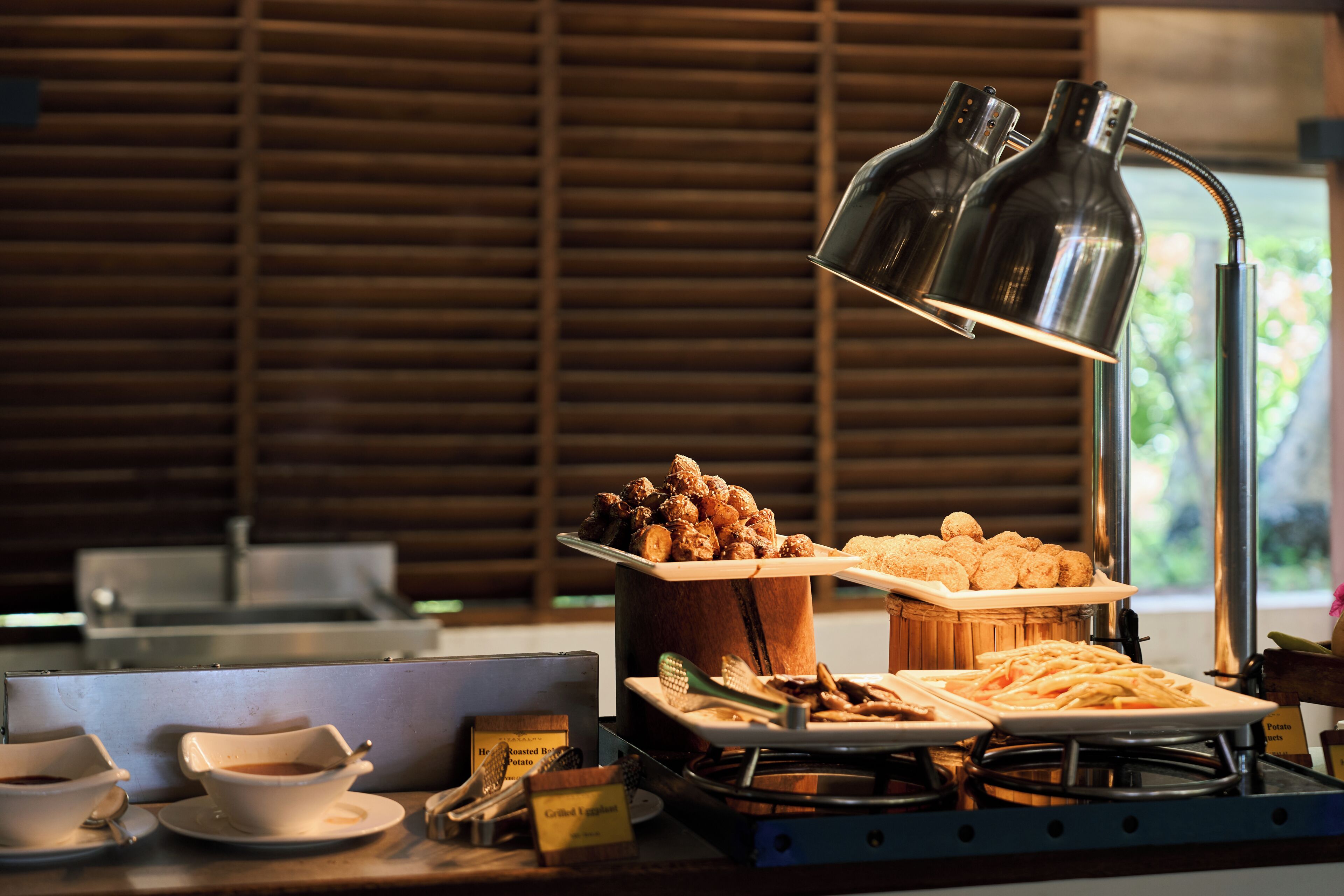 A buffet setup with various food items, a coffee station, and a modern lamp.