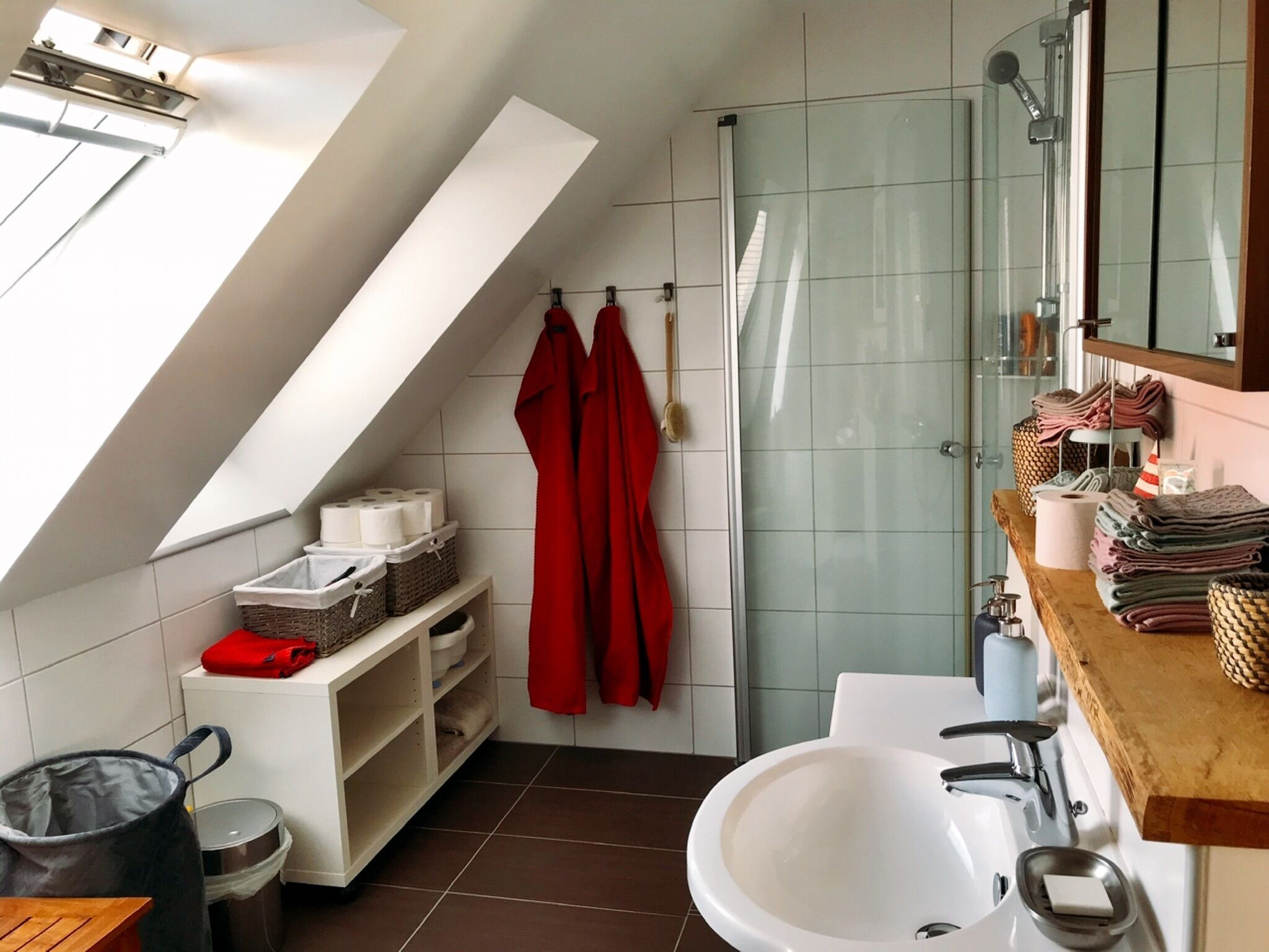 A modern bathroom with a skylight, a shower, and a sink.