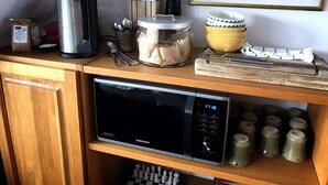 A kitchen counter with a microwave, a coffee maker, a jar of sugar, a knife block, and a framed picture on the wall. - Villa Lindell (Hoganas)