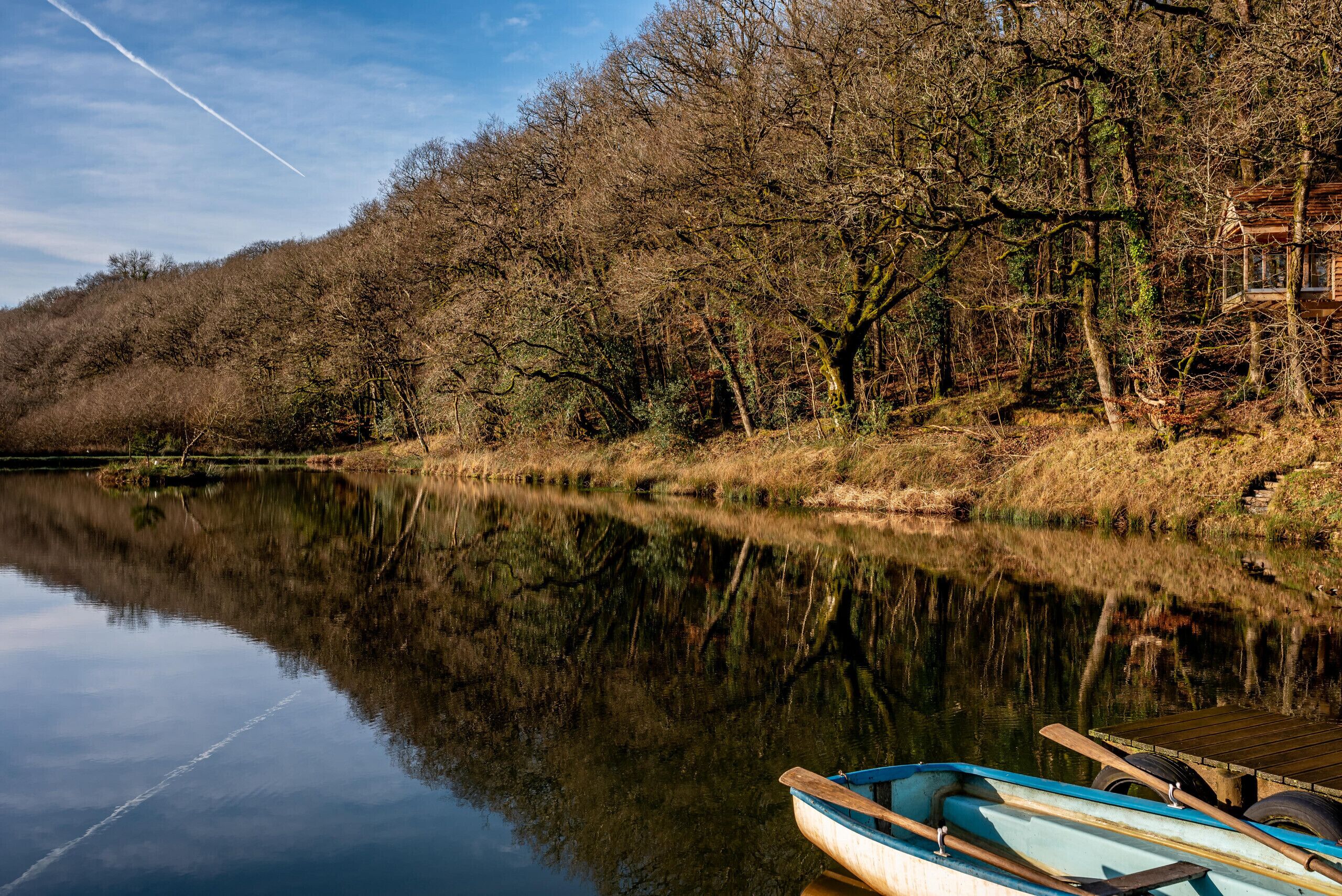 Un río tranquilo con un muelle de madera y un pequeño bote.