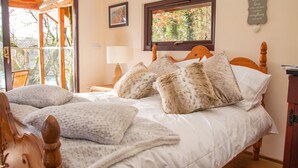 A bedroom with a wooden bed, white bedding, and a window with a view of trees.
