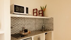 Eine kleine Küche mit Mikrowelle, Spüle und einem Kühlschrank.
