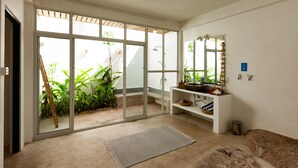Ein modernes Badezimmer mit einer großen Schiebetür zum Garten, einem weißen Waschbecken inklusive Spiegel und einem beigen Teppichboden.