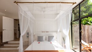 Ein Schlafzimmer mit einem Bett, weißen Vorhängen und einem Holztisch.