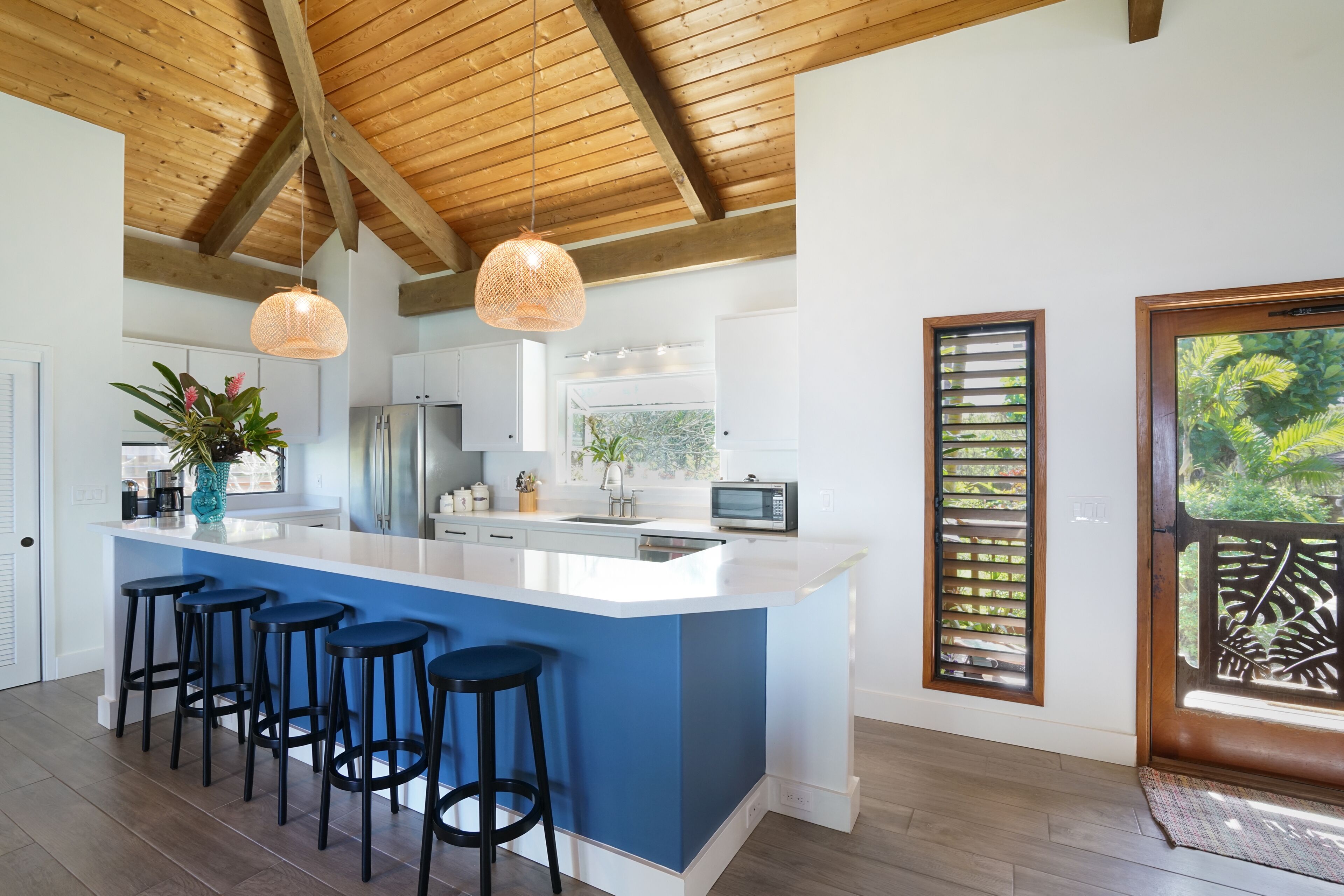 A modern kitchen with a large island, bar stools, and pendant lighting.