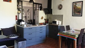Una cucina compatta con forno a microonde, lavello e un piccolo angolo ristoro con tovaglia colorata.