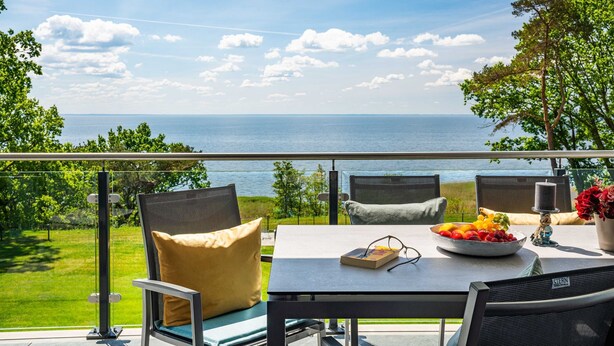 A terrace with a table, chairs, and a view of the sea.