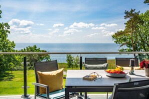 Una terraza con mesa, sillas y vista al mar.