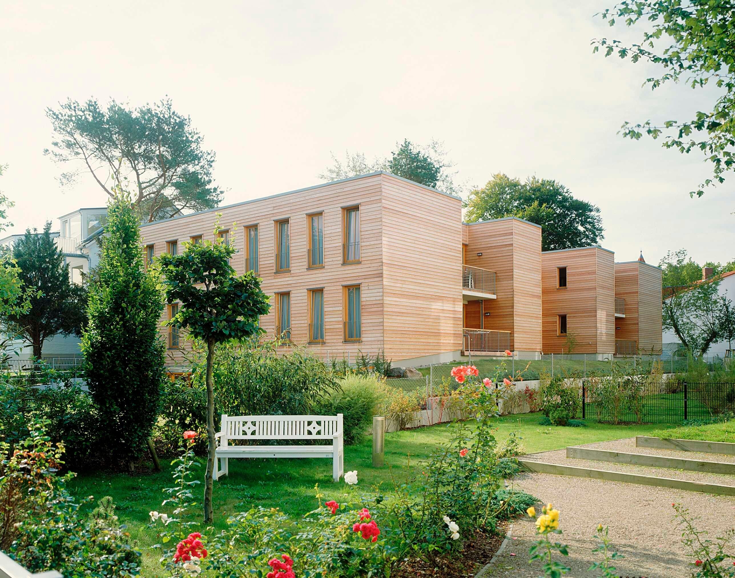A modern building with a flat roof, multiple windows, and a small balcony.