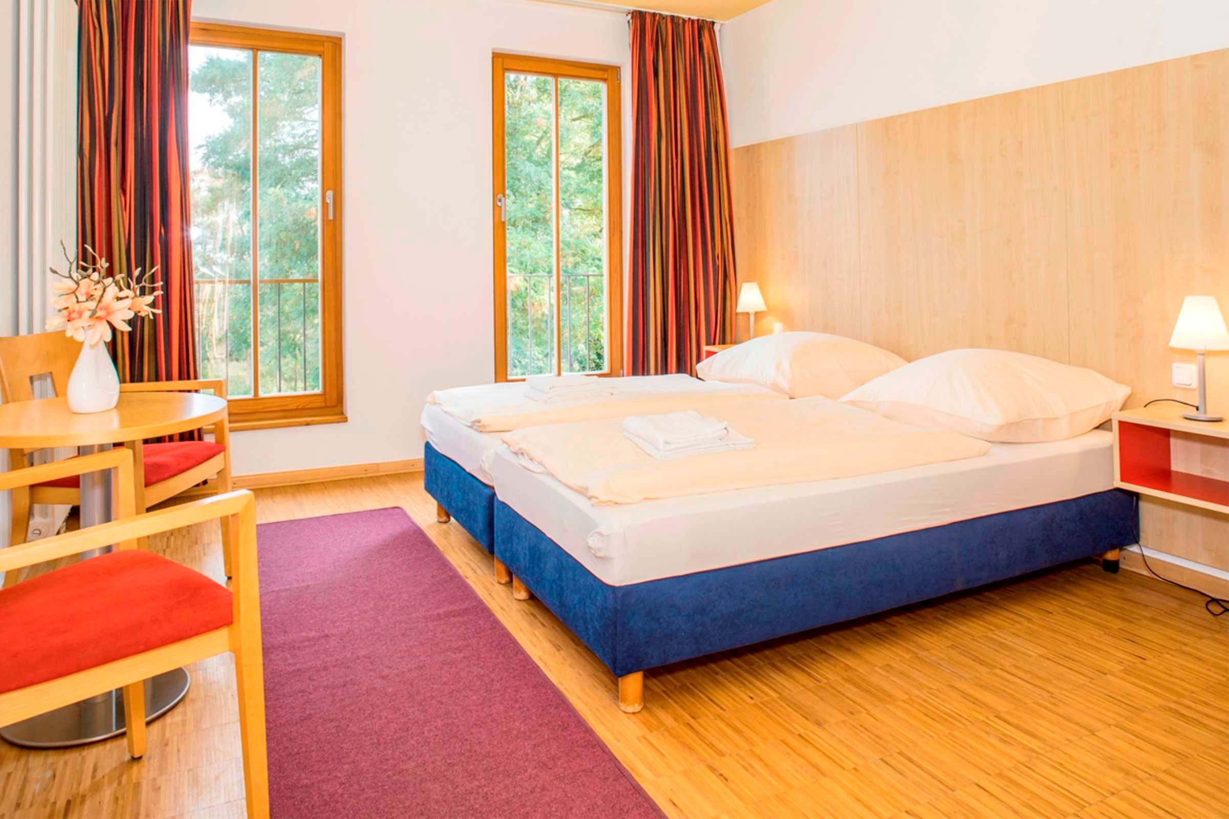 Ein Hotelzimmer mit Bett, Schreibtisch, Stuhl und einem Fenster mit Vorhängen.