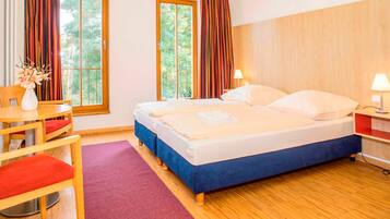 Ein Hotelzimmer mit Bett, Schreibtisch, Stuhl und einem Fenster mit Vorhängen.