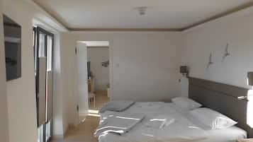 Un dormitorio con una cama grande, una mesita de noche, un espejo y una puerta que da a otra habitación.