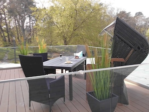 Un espace extérieur aménagé pour les repas, avec une table, des chaises et des plantes en pot.
