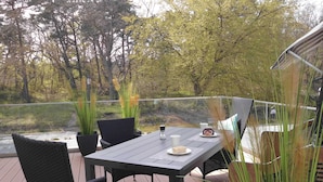Una terraza con mesa y sillas, con vistas al agua y a los árboles.