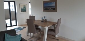 Ein Essbereich mit einem Holztisch, vier Stühlen, einem blauen Teppich und zwei Wandleuchten.