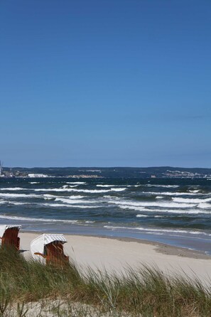 Une plage avec des vagues, une chaise et un bâtiment en arrière-plan.