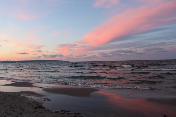 A beach with waves and a sunset sky.