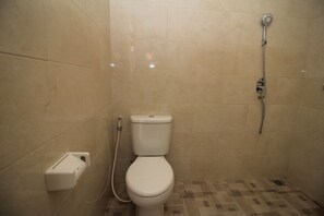 A small, tiled bathroom with a toilet, a shower, and a wall-mounted soap dispenser. - Brata Cottage Bisma Ubud by Summer Stay (Ubud)