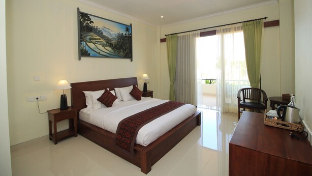 A hotel room with a large bed, a desk, a chair, and a painting on the wall. - Brata Cottage Bisma Ubud by Summer Stay (Ubud)