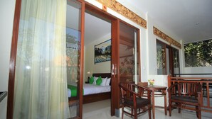A hotel room with a bed, a desk with a chair, and a sliding glass door leading to a balcony. - Brata Cottage Bisma Ubud by Summer Stay (Ubud)