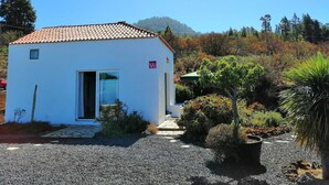 A small white building with a tiled roof, a door, and a small window.