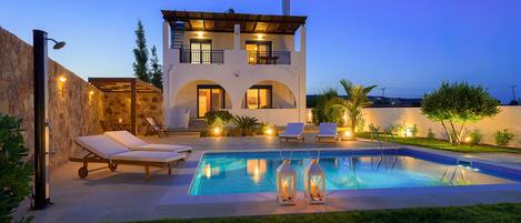 Een buitenzwembad, ligstoelen bij het zwembad