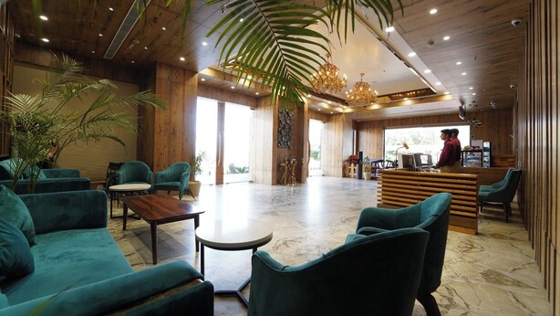 A spacious lobby with wooden walls, a reception desk, and green upholstered seating.