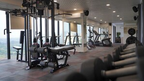 A gym with various exercise equipment, large windows, and a view of the outdoors.