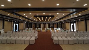A conference room with rows of white chairs, a central stage, and a red carpet.