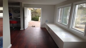 A hallway with a bench, large windows, and a door leading to a room. - Huge House Fantastic for Families and friends (Anglers Reach)